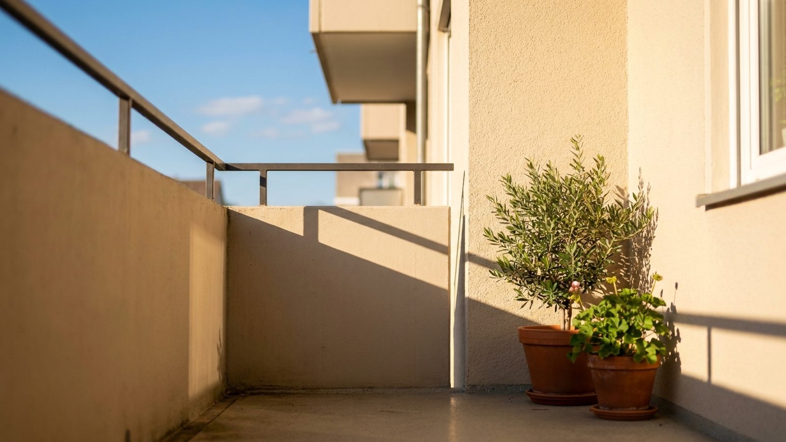 Sonniger Balkon mit Topfpflanzen an heller Putzfassade