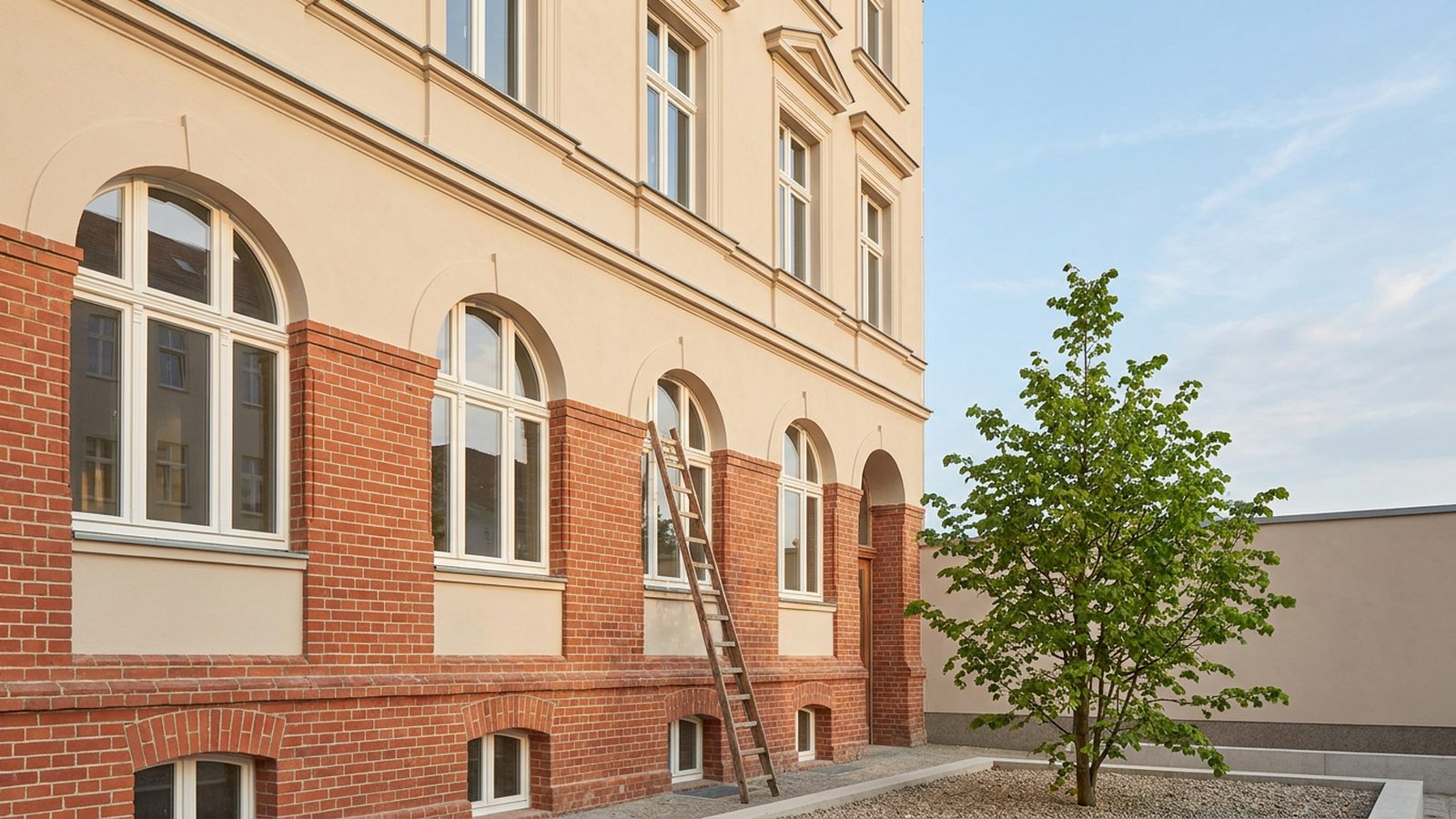 Frisch sanierte Altbaufassade mit Leiter im Sonnenlicht